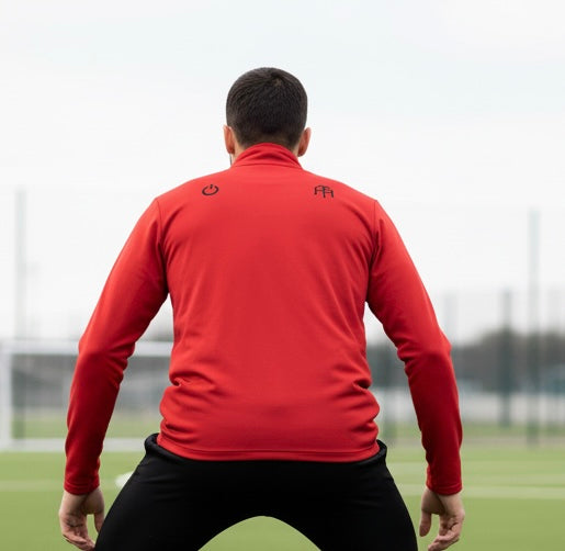 Soccer player prepares to run drills on turf while wearing a Red Soccer Edition lightweight quarter-zip pullover in breathable 3.8 oz performance fabric — An Athlete Trains soccer warmup gear | Our Game Collection 