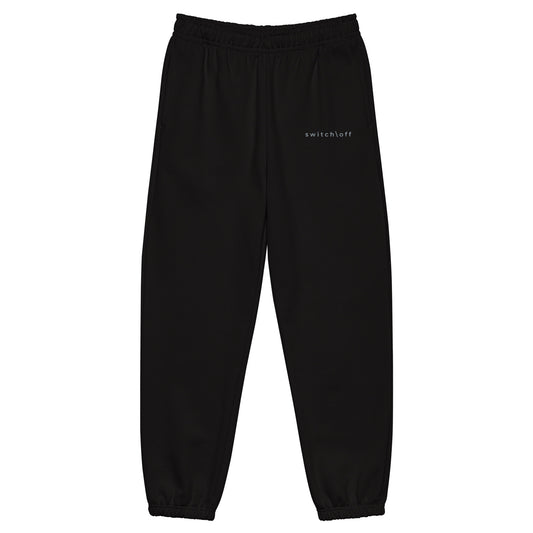 90s style boxy heavyweight sweatpants in black color with gray switch\off embroidery - An Athlete Trains. Front view 